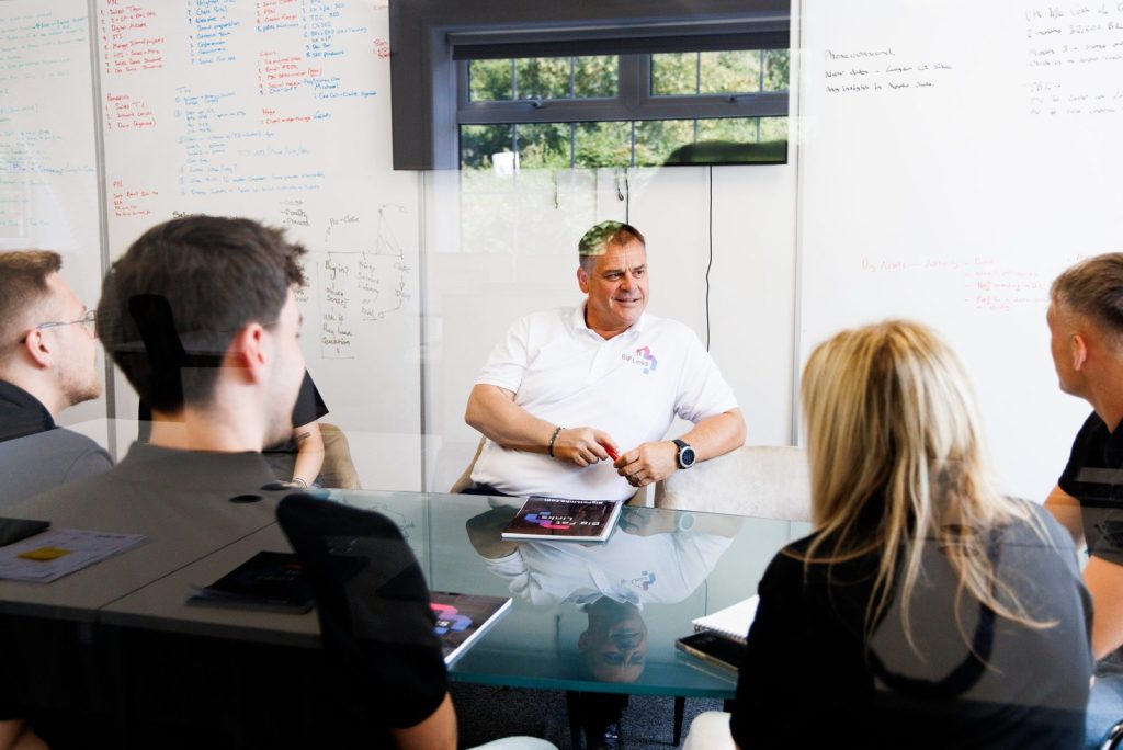 group of people in a meeting sat around a glass table